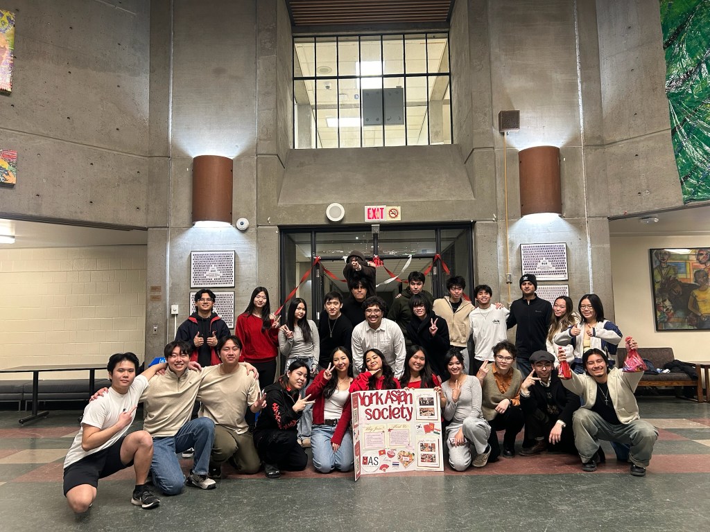 Students gathering for a group photo behind a York Asian Society sign to celebrate the club's orientation event.